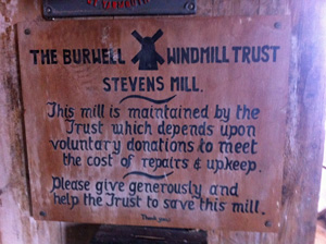 Photo of old plaque that reads: The Burwell Windmill Trust - Stevens Mill - This mill is maintained by the Trust which depends upon voluntary donations to meet the cost of repairs & upkeep. Please give generously and help the Trust to save this mill. Thank you. Ends