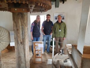 A volunteer guide with two visitors inside the mill.